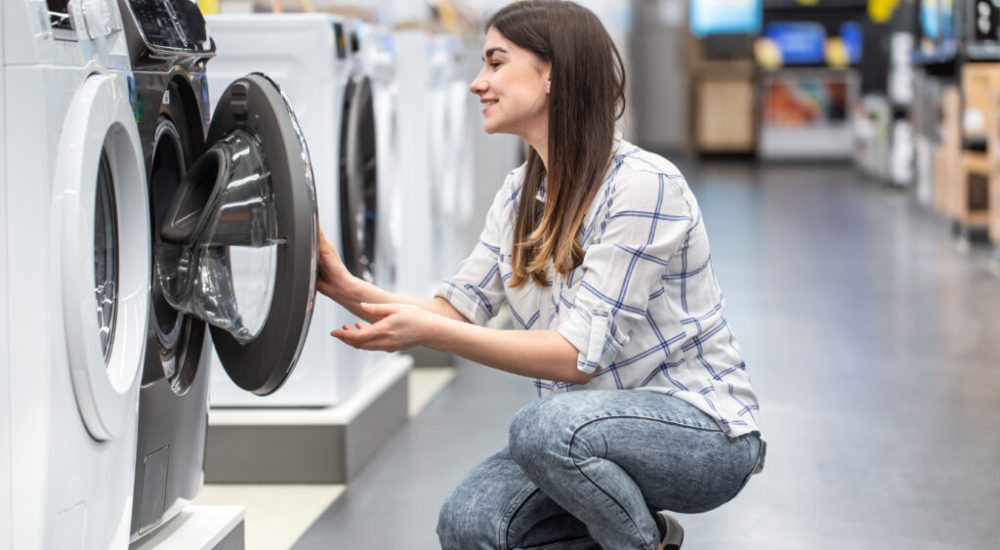 A young woman in a store chooses a washing machine.. The concept of shopping.